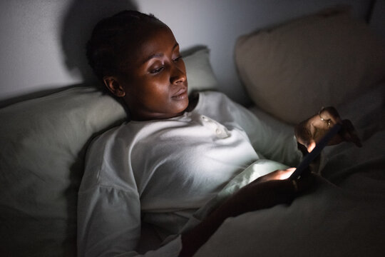 Black woman browsing mobile phone at night