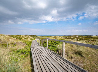 Fototapeta na wymiar Wooden boardwalk along the dune landscape near Rantum, Sylt, Schleswig-Holstein, Germany