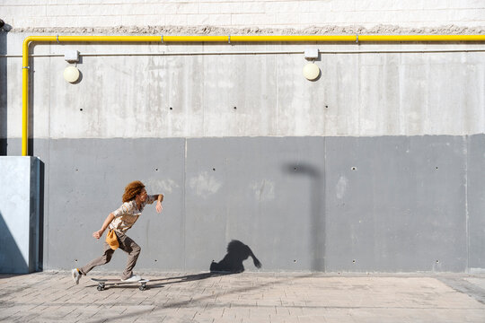 Energetic man skateboarding on street