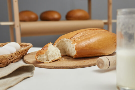Bakehouse countertop with fresh baked bread and ingredients for preparing dough, copy space for promotional text