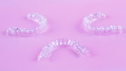 Invisible dental teeth brackets tooth aligners on pink background. Plastic braces dentistry...