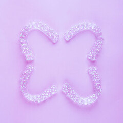 Invisible dental teeth brackets tooth aligners on pink background. Plastic braces dentistry retainers to straighten teeth.