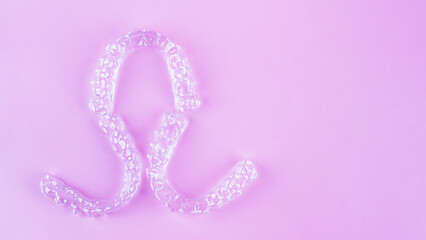 Invisible dental teeth brackets tooth aligners on pink background. Plastic braces dentistry...
