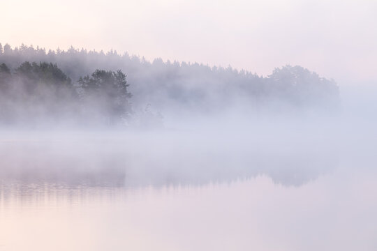 Fototapeta Dawn over a fog covered lake