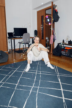 Young woman with soap bubbles on rug