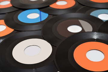 Pile of 45 rpm old vinyl records on the white table. Vintage technology concept. Selective focus.

