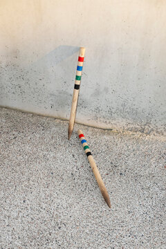 Wooden croquet sticks with stripes with colours on a concrete wall