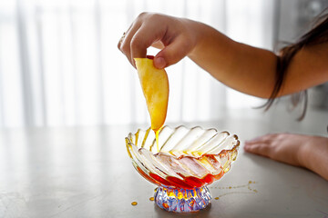 Rosh Hashanah Sweet Tradition. Young Girl's Hand Dips Apple in Honey.