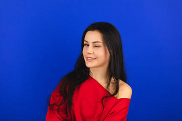 Playful happy contented brunette woman wear red long top blinking eye, looking at camera with...