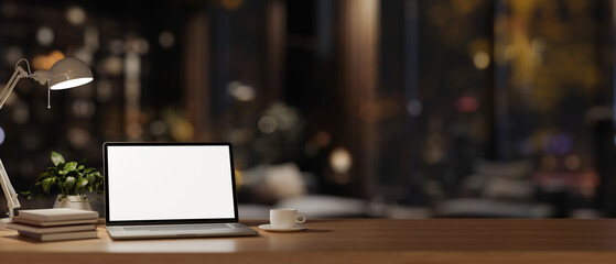 An office desk workspace in a modern dark office room at night features a laptop computer mockup.