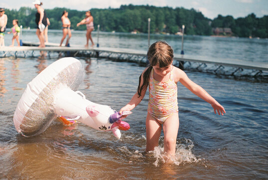 happy girl with a unicorn floaty at the lake in summer