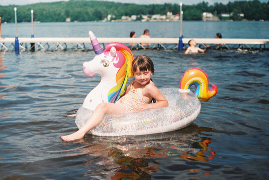 happy girl with a unicorn floaty at the lake in summer