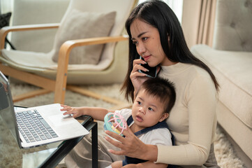 A positive Asian businesswoman mom is talking on the phone while taking care of her little son.