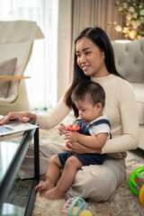 A businesswoman mom is playing with and taking care of her baby boy while working on her laptop.