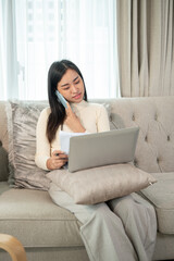 A businesswoman is multitasking, talking on the phone, and focusing on her laptop, working from home