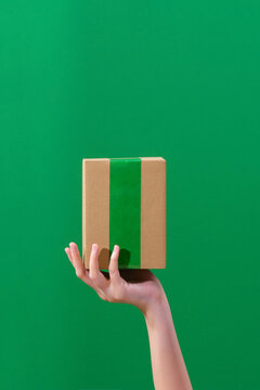 Hand holding small paper carton over green background