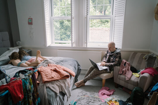Father working remotely from messy room with kids
