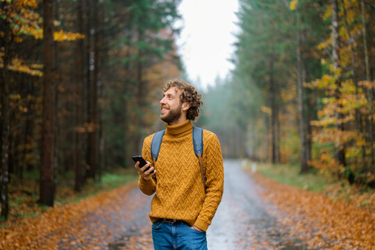 Man with smartphone in the forest in autumn after the rain 
