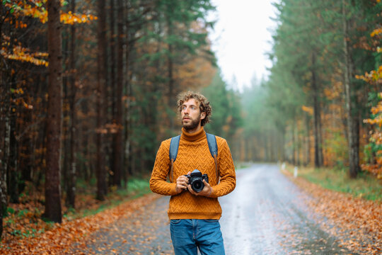 Man with vintage camera in the forest in autumn after the rain 