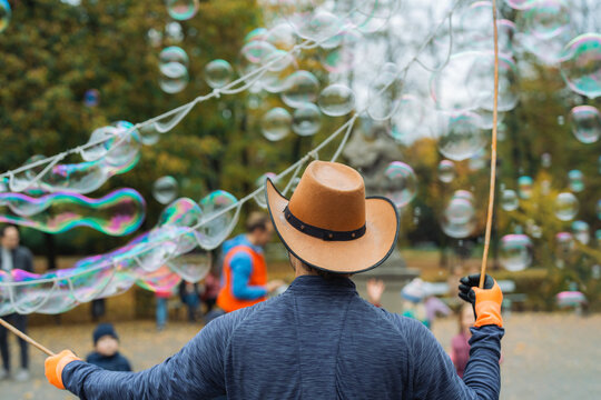 Man in cowboy hat blowing huge bubbles 