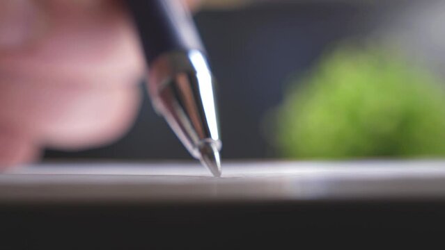 Business person signs a contract with a ballpoint pen. Shallow depth of field, close-up view