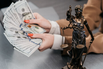 A young woman lawyer at the workplace counts money. Concept of corruption, bankruptcy court, bail,...