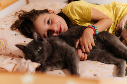 Kid cuddling a cat in bed at night. Goodnight