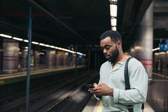 A man using his mobile phone while waiting on the subway platform.