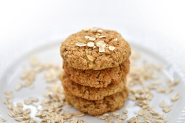 Oatmeal cookies tower made with oat flakes on plate on white background. Healthy food for breakfast or a snack. Close up. Soft focus