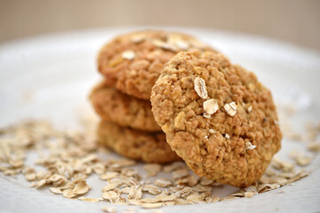 Oat cookies with oat flakes on a white plate. Healthy food for breakfast or a snack. Close up. Soft focus