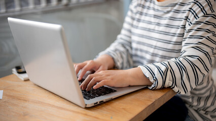 A close-up image of a female freelancer working remotely at a coffee shop, working on her laptop.