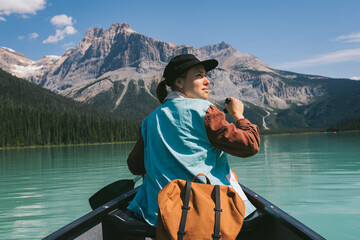 Beautiful young female canoeing through clear glacier water