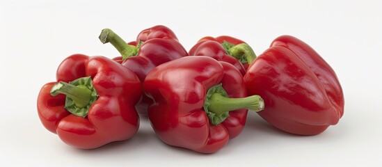 A cluster of vibrant red bell peppers is arranged neatly on a clean white surface, showcasing their glossy skin and distinct shape. The peppers are grouped closely together, creating a visually