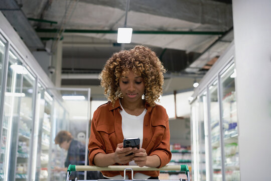 A black woman buys in a supermarket from a grocery list