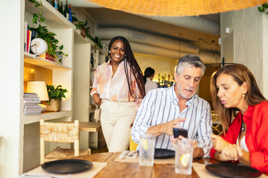 Friends using their smartphones while waiting at a restaurant.