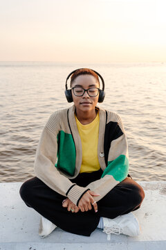 Female relaxing while sitting on stone border on city embankment