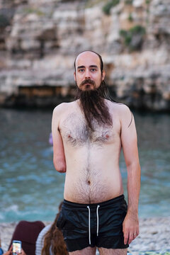 Portrait of a handsome bearded male model with long hair on the beach
