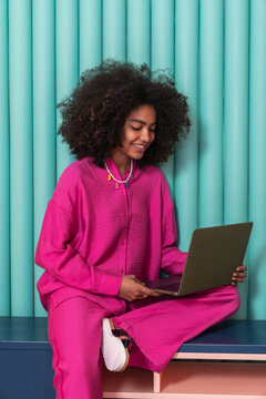 Smiling Woman with Laptop in Vibrant Setting