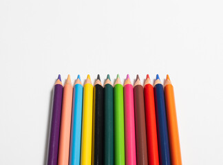 Buntstifte in verschiedene Farben aufgereiht auf weißen Hintergrund