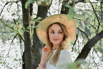 Wiosenny portret młodej ładnej kobiety w kapeluszu, w parku , wśród drzew.