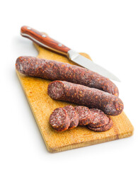 Sliced salami sausage on cutting board isolated on white background.