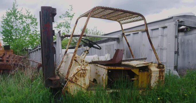 A pallet stacker left in the grass rotting and rusting away in slow motion.