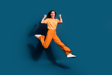 Fototapeta na wymiar Full length body photo of overjoyed winner energetic girl sports competition raised fists up isolated over dark blue color background