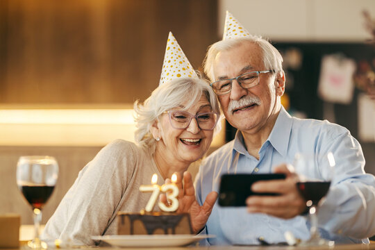 A senior couple is having video call on phone on a birthday at home.