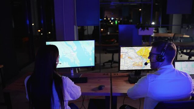 Two delivery operators sitting at desk in office monitoring cargo transportation