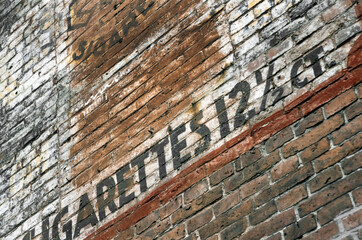Brick wall with faded cigarettes advertising in France. Eighties.