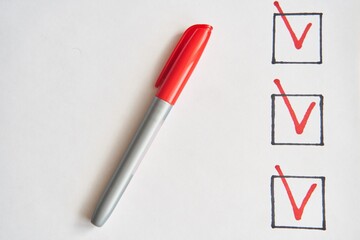 Checklist marked red with a red pen. Close up shot of filled check boxes with red pen