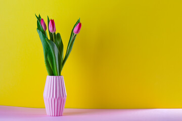 bouquet of pink tulips in a vase on a yellow background