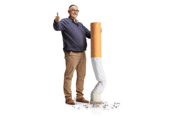 Full length portrait of a happy mature man putting off a big cigarette and gesturing thumbs up