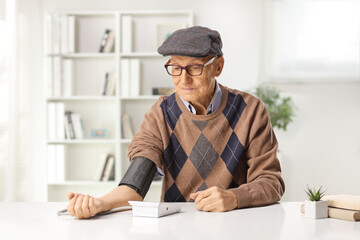 Elderly man sitting at home and checking blood pressure